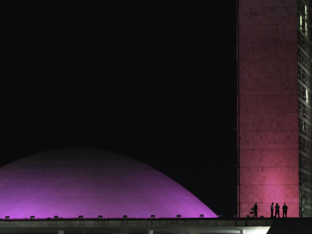 Imagem mostra o Congresso Nacional, com foco na parte do Senado, iluminado de rosa por causa do "Outubro Rosa", mês de conscientização sobre o câncer de mama